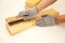 Hand wire brush men`s hands in protective gloves on vintage wooden Board. Aging wooden boards by brushing. White background.