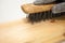 Hand wire brush men`s hands in protective gloves on vintage wooden Board. Aging wooden boards by brushing. White background.