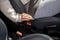 Hand of woman buckles down seat belt in car