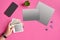 Hand of woman holding snapshot pictures, smartphone, sheets of cardboard, binder clips and succulent on pink background