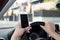 Hand of woman holding steering wheel and mobile phone driving car while texting distracted in risk