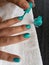 hand of woman painting her nails in aquamarine color