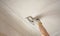 Hand of a woman plasterer repairs the ceiling with plaster