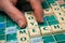 hand of woman playing with plastic letters to forming a word on Scrabble board game