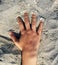 A hand of woman posed over the sand of a spanish beach