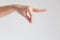 A hand of woman posturing thumb and forefinger touch together and other finger stretch forward on white background