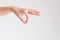 A hand of woman posturing thumb and forefinger touch together and other finger stretch forward on white background