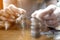 Hand of woman put a silver coin on top of two pile for stacking on the wooden table