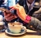 Hand of woman with red gel nails and pink wristwatch using smartphone in cafe