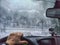 Hand of woman on steering wheel in car and and the forest with cloudy windshield, fogged with snow ice in winter