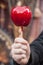 Hand of woman with sweet candy red apple at the chri