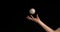 Hand of Woman Throwing a Ball of Baseball against Black Background