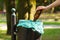 Hand of woman throwing glass bottle into recycling bin, littering of environmental