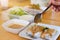 Hand of woman using spoon to eat thai rice noodles with curry in restaurant.