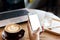 Hand woman using a telephone, empty screen smart phone and computer on wooden table In the coffee shop