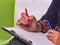 Hand of a woman writing on paper with a red felt pen.