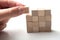 Hand with wooden brick of construction game on white