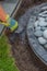 Hand with work glove filling gritting material into the curb of a garden fountain