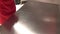 Hand of worker cleans metal table for food production.