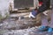 Hand of worker with gloves hammering down plaster on facade that crumbles due to moisture and mold underneath a white wooden frame