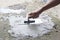 Hand of worker holding plastering trowel by leveling the concrete floor smooth.