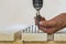 Hand of a worker screws a in a wooden board with a cordles