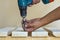 Hand of a worker screws a in a wooden board with a cordles