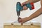 Hand of a worker screws a in a wooden board with a cordles