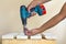 Hand of a worker screws a in a wooden board with a cordles