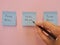 The hand writes with a felt-tip pen on blue stickers-fake news. On a pink background, blue stickers with the inscription - fake ne