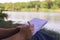 Hand writes Notepad pen pencil near the lake in the Park in Sunny day