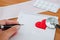 Hand writes on a notepad. Stethoscope, heart, pills, cardiogram on a wooden background