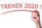 Hand writes word trends 2020 with red marker