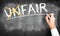 Hand writes the word unfair and crosses the UN, changing the word to fair