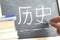 Hand writing on a blackboard in Chinese History class with the word History written on. Some books and other materials