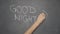 Hand writing `GOOD NIGHT` on black chalkboard