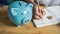 A hand is writing on note book, piggy bank and  coins on wooden table