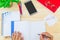 Hand writing on notebook on wooden desk with office supplies, smartphone, glasses and green leaves pot