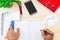 Hand writing on notebook on wooden desk with office supplies, smartphone, glasses and green leaves pot