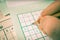 Hand is writing numbers in grid of popular logic game sudoku