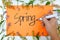 A hand writing spring season welcome greeting poster in orange colored paper with flowers border. Start of springtime