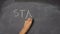 Hand writing `VOTE, YES, NO, STAY, LEAVE` on black chalkboard