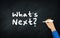 Hand writing What`s next? Question On Chalkboard. Business Question and Next Actions Concept. Anticipation and Expectation