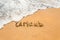 Hand written text in German Urlaub English translation holidays on the golden beach sand with coming wave