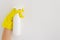 Hand with yellow glove holding a blank white spay bottle closeup on clean background. Mock up bottle clean. Copy space