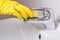 Hand in yellow glove with sponge cleaning sink