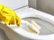 hand a yellow glove with white toilet brush does cleaning the toilet