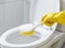 hand a yellow glove with white toilet brush does cleaning the toilet