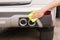 Hand with yellow microfiber cloth cleaning big white taillight c