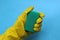 Hand in yellow rubber glove holding a sponge for washing